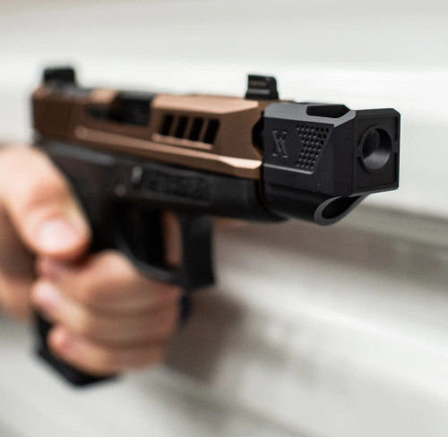 True Precision Glock 43X with copper slide and black threaded barrel and Compensator being held against white metal background close up of the compensator.