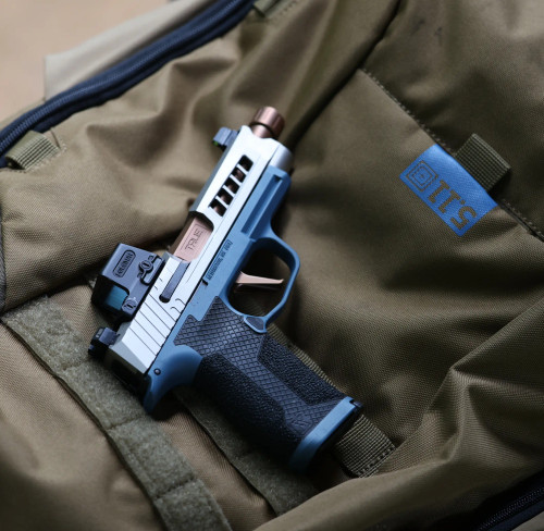 A Sig P365 XL with a Copper TiCN threaded barrel, stainless slide and hybrid hand stippled lower, laying on top of a green range bag.