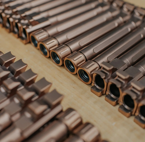 True Precision threaded barrels for the Sig P365 XL in copper TiCN organized on a wooden table