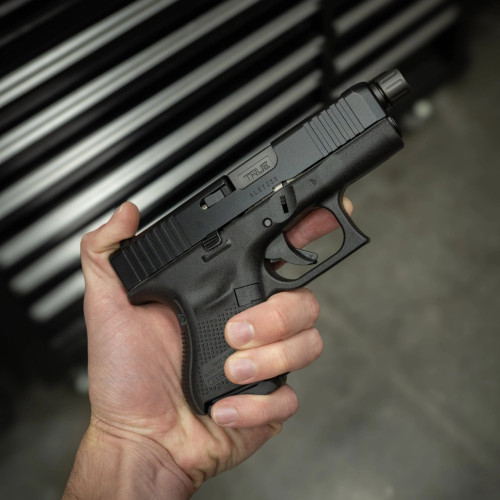 True Precision Glock 26 with Stealth Grey Threaded barrel, being held above a tool box True Precision Glock 26 with Stealth Grey Threaded barrel, being held above a tool box