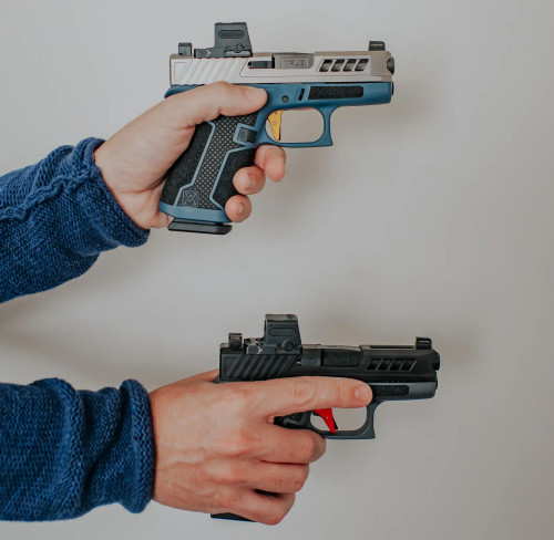 Two Glock 43s with Threaded True Precision non-threaded barrels being held over a grey background