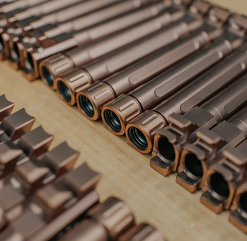 Threaded copper TiCN Glock 19 barrels lined up on a table