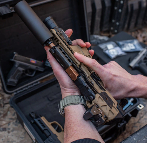 A Sig P320 Compact FLUX Raider, with True Precision threaded copper TiCN barrel, and black suppressor, with a gun case in the background.