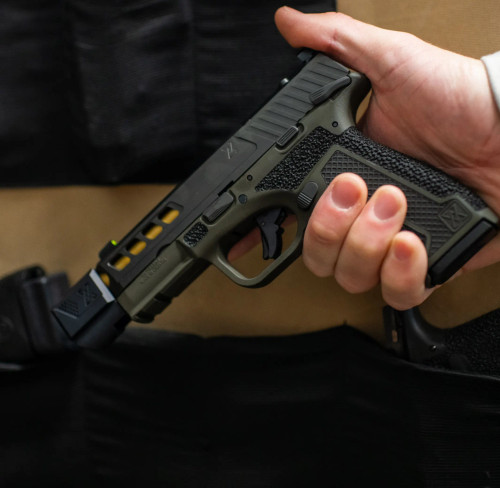 A Springfield Hellcat Pro with True Precision gold TiN threaded barrel and True-Lock compensator being put into a safe