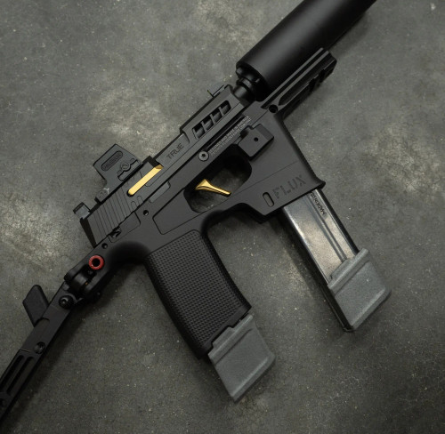 True Precision P365 Flux Extended 6.5" barrel with a black suppressor, on concrete background with gold extractor and trigger