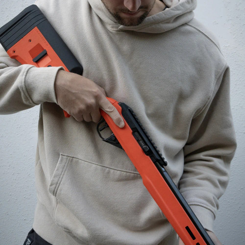A person holding the TRUE Hunter TP/22 with black nitride bull barrel and Hunter Orange stock.