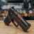 A Sig Sauer P320 Compact with a True Precision non-threaded copper TiCN barrel and black DLC Axiom slide sitting on a wooden table with raw steel bars in the background