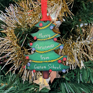 Wooden Christmas tree decoration in the shape of a christmas tree, with custom bauble decorations and custom text hanging with red ribbon from a real christmas tree Wooden Christmas tree decoration in the shape of a christmas tree, with custom bauble decorations and custom text hanging with red ribbon from a real christmas tree