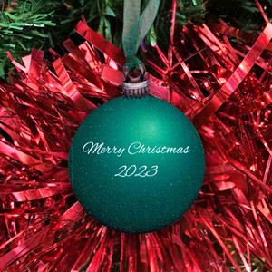 Green Wooden Bauble with text 'Merry Christmas 2023' hanging on a christmas tree Green Wooden Bauble with text 'Merry Christmas 2023' hanging on a christmas tree