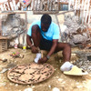 Haitian Metal Artisans in Croix-des-Bouquets cleaning, burning, flattening used oil barrels to use for metal art. Haitian metal artist sketching design in