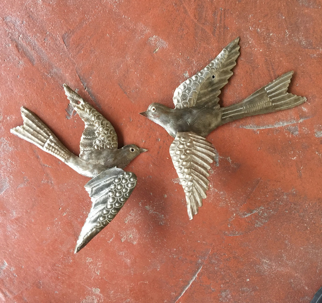 Haiti metal birds with 3-d wings hung on stucco wall