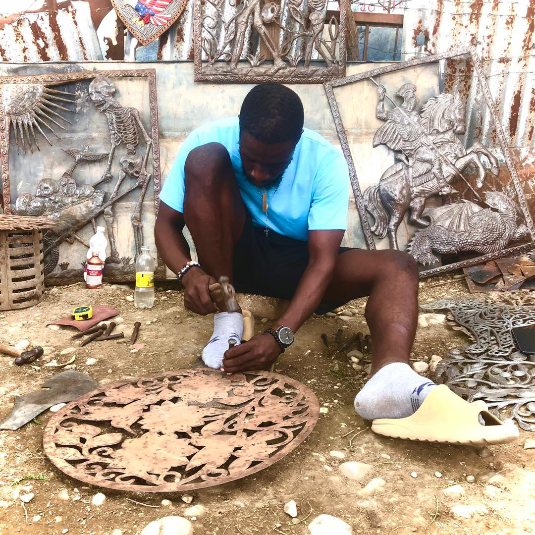 Haitian Metal Artisans in Croix-des-Bouquets cleaning, burning, flattening used oil barrels to use for metal art. Haitian metal artist sketching design in