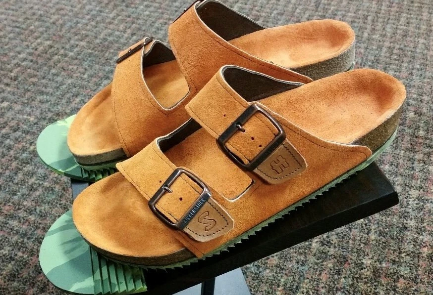 Tan suede Birkenstock sandals with two adjustable buckle straps, personalized leather patches, and cork footbeds.