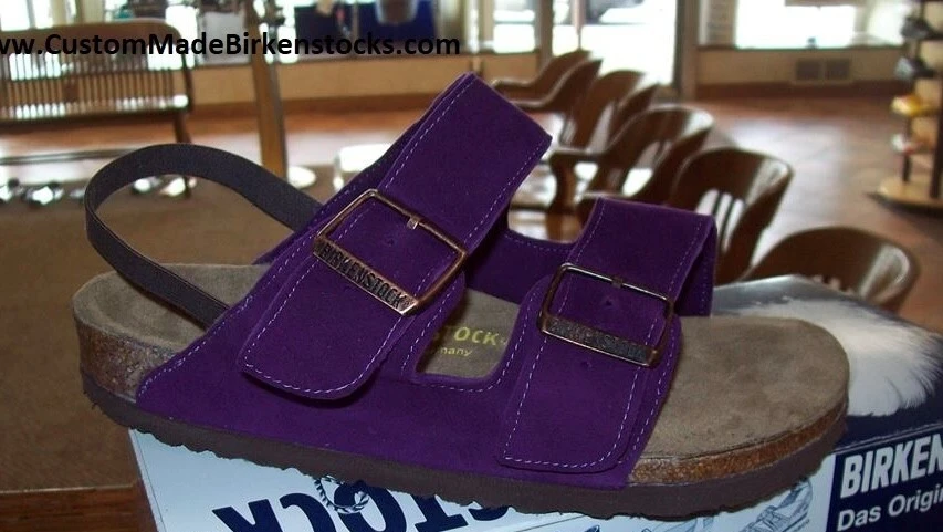Purple suede Birkenstock sandals with two adjustable buckle straps and cork footbeds.