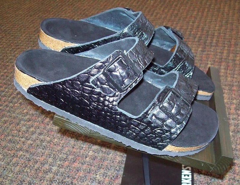 Black crocodile-textured Birkenstock sandals with two adjustable straps and dark footbeds.