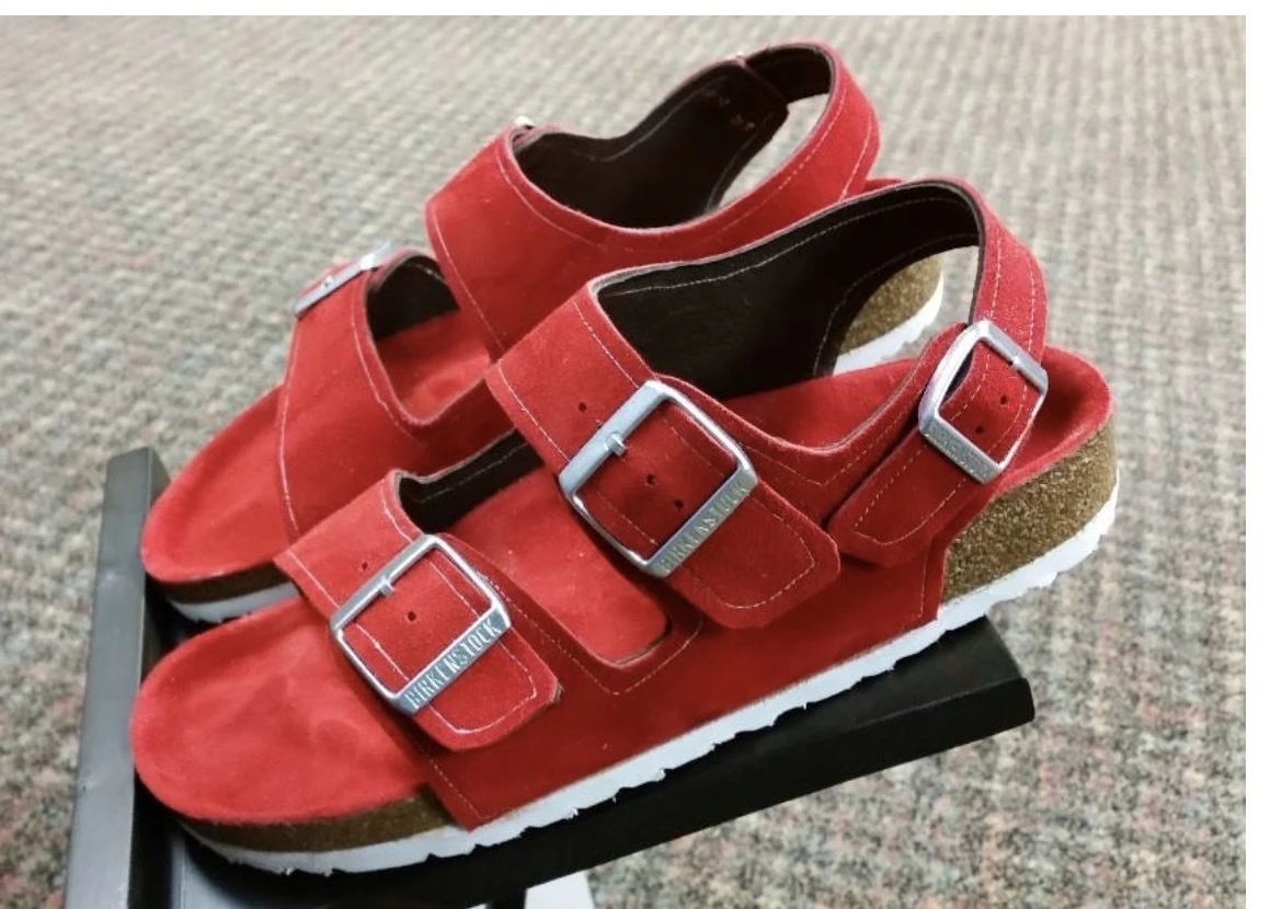 Red suede Birkenstock sandals with three adjustable buckle straps, back straps, and white soles.
