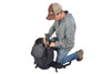 Man kneeling beside Kelty Redwing 44 Tactical backpack, packing gear into the main compartment of pack