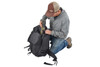 Man kneeling beside Kelty Redwing 50 Tactical backpack, putting gear inside the pack