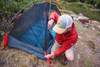 Man in red jacket setting up the Kelty Late Start 1 person tent in the woods