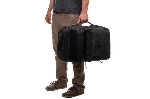 Man holding Kelty Nomad travel pack with side handle