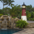 Amish crafted poly garden lighthouse, Barnegat Replica, in black, cherrywood, white, pictured in flower bed by pool waterfall.