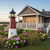 Amish crafted poly garden lighthouse, Barnegat Replica, in black, cherrywood, white, pictured in flower bed by beach house.