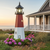 Amish crafted poly garden lighthouse, Barnegat Replica, in black, cherrywood, white, pictured in flower bed by beach house.
