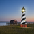 Amish made Cape Hatteras replica garden lighthouse finished in black and white with cherrywood and weatherwood base, pictured in seagrass at boathouse.