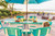 Surf-Aira 8 Foot Poly Surfboard Bar Table and Chairs Set in White and Aruba Blue pictured on a deck.