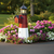 Poly lighthouse with mailbox, amish crafted, pictured in flowerbed beside road.