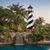 Amish made Cape Hatteras replica garden lighthouse finished in black and white with cherrywood and weatherwood base, pictured by pool waterfall.