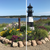 Amish made poly garden lighthouse well casing cover in lake front flower bed.