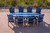 Surf-Aira Amish crafted poly dining table & Ocean Wavz chairs in patriot blue and light gray, pictured on deck at the shore