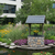 Amish handcrafted stone and poly wishing well, size jumbo, coastal gray frame with black, gray stone with black grout, black shakes. Pictured beside a koi pond in corporate courtyard.