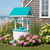 Amish crafted poly wishing well in aruba blue and white, pictured in flower bed at beach house.