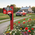 Fire fighter mailbox in flower bed at end of drive with house and pickup truck in background