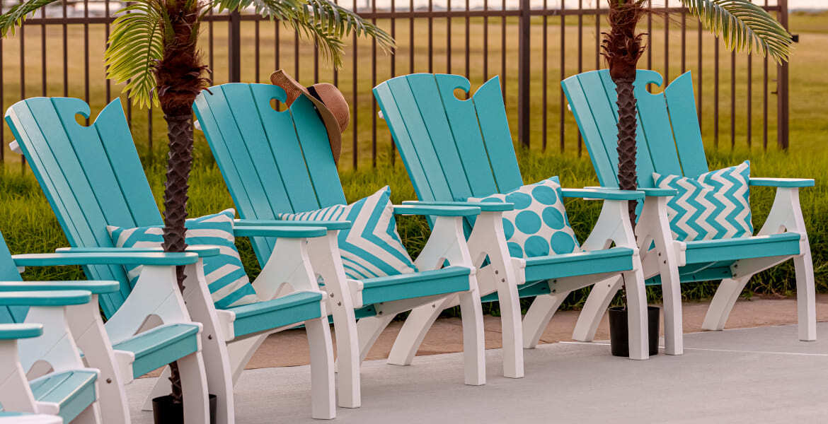 Six amish crafted poly blue and whte adirondack chairs lined up poolside.