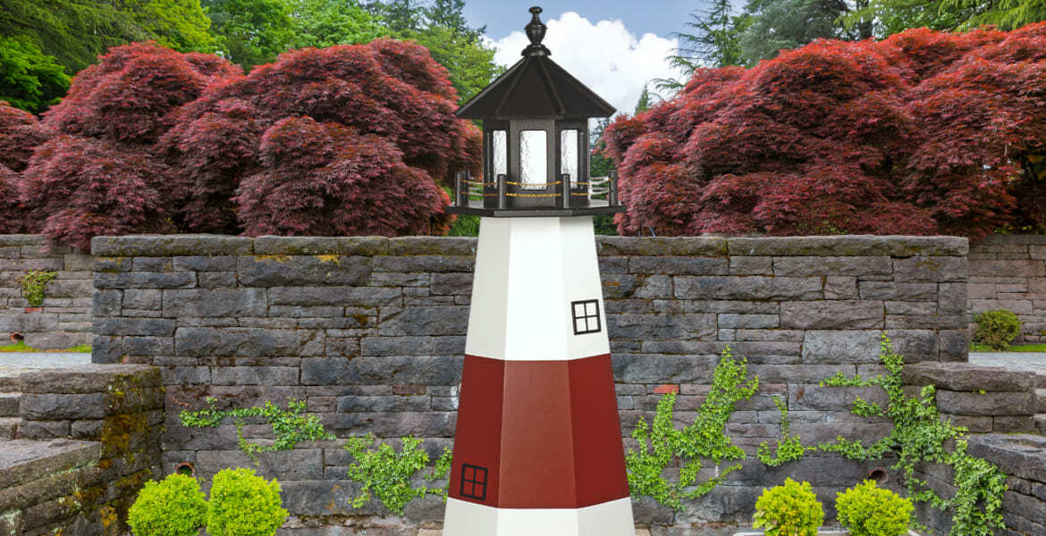 poly garden lighthouse in flower garden with rock wall backdrop