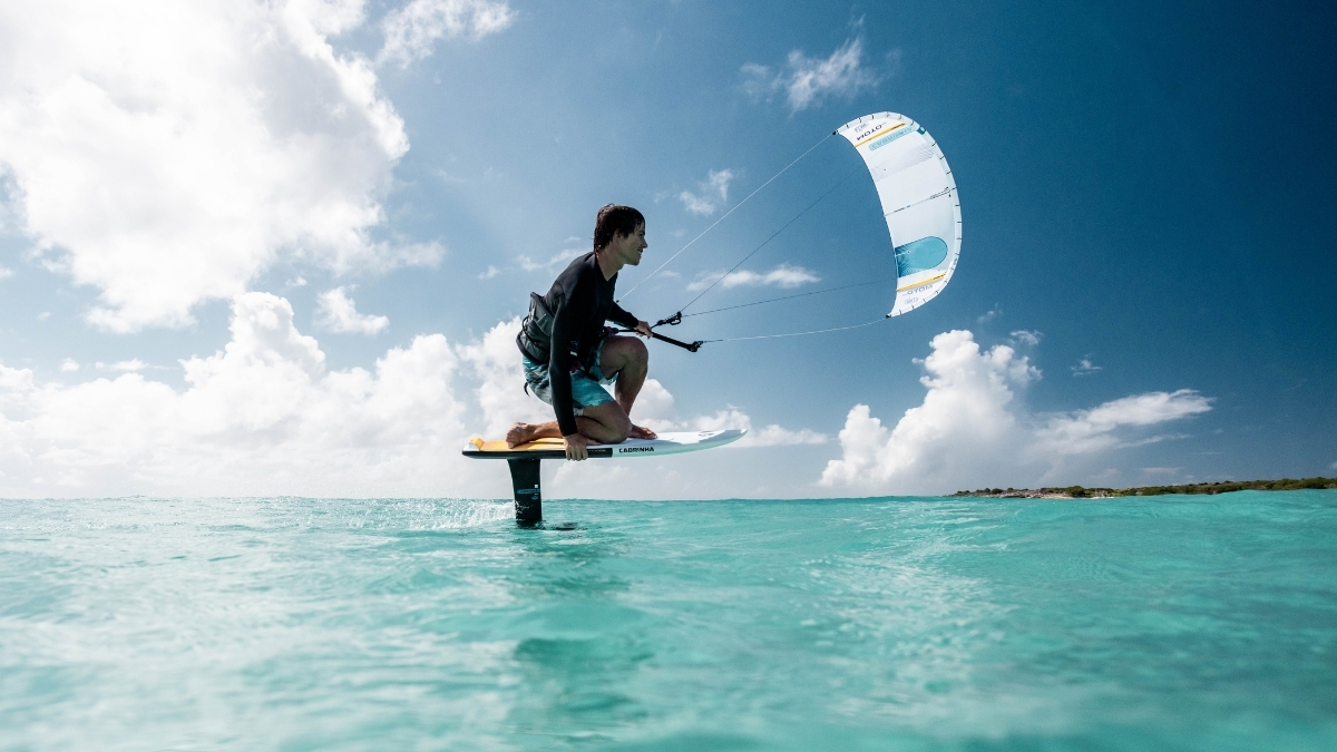 2026 Cabrinha Moto Apex rider foiling on a Cabrinha hydrofoil board in turquoise flatwater
