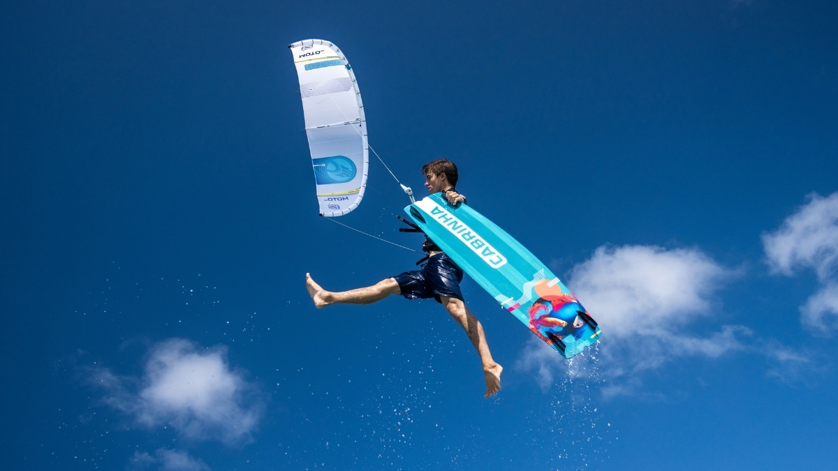 2026 Cabrinha Moto Apex kite rider boosting high with a Cabrinha twin tip against a deep blue sky