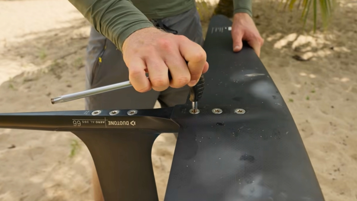 Rider tightening hydrofoil mast screws with a hex wrench before a dockstart session