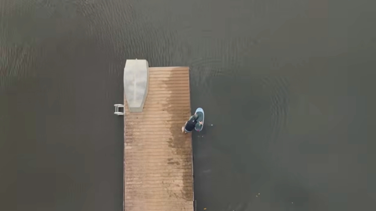 Aerial view of a pump foiler at the end of a wooden dock preparing to dockstart a foil board