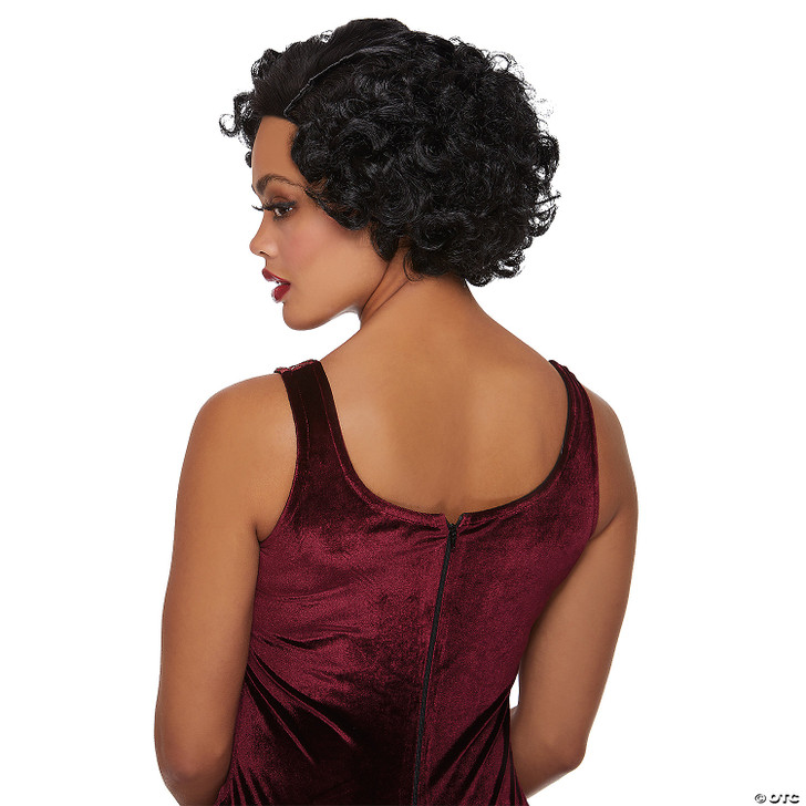 Black short curly flapper wig shown from the back on a model wearing a burgundy velvet dress, with finger-wave styling at…