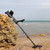 Nokta Impact Metal Detector leaning against rock on beach