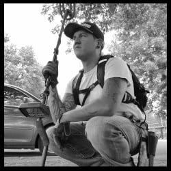 Tennessee Adventures Matt Ryan Holding Fisher Metal Detector with Trees and A Car in the Background all in Black and White