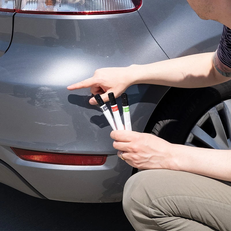 Person applying touch up paint to a small area on a vehicle.