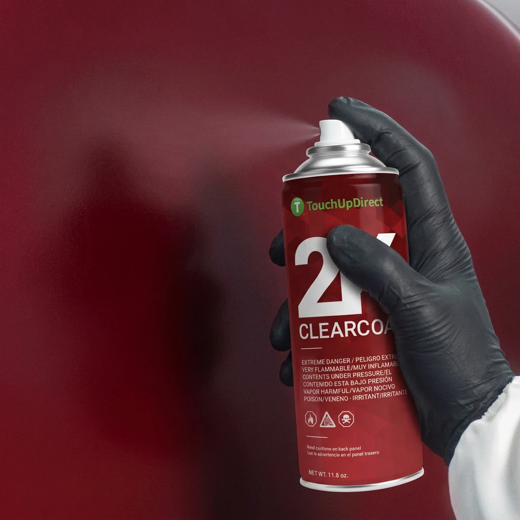 Black-gloved hand spraying 2K clearcoat onto a red vehicle panel.