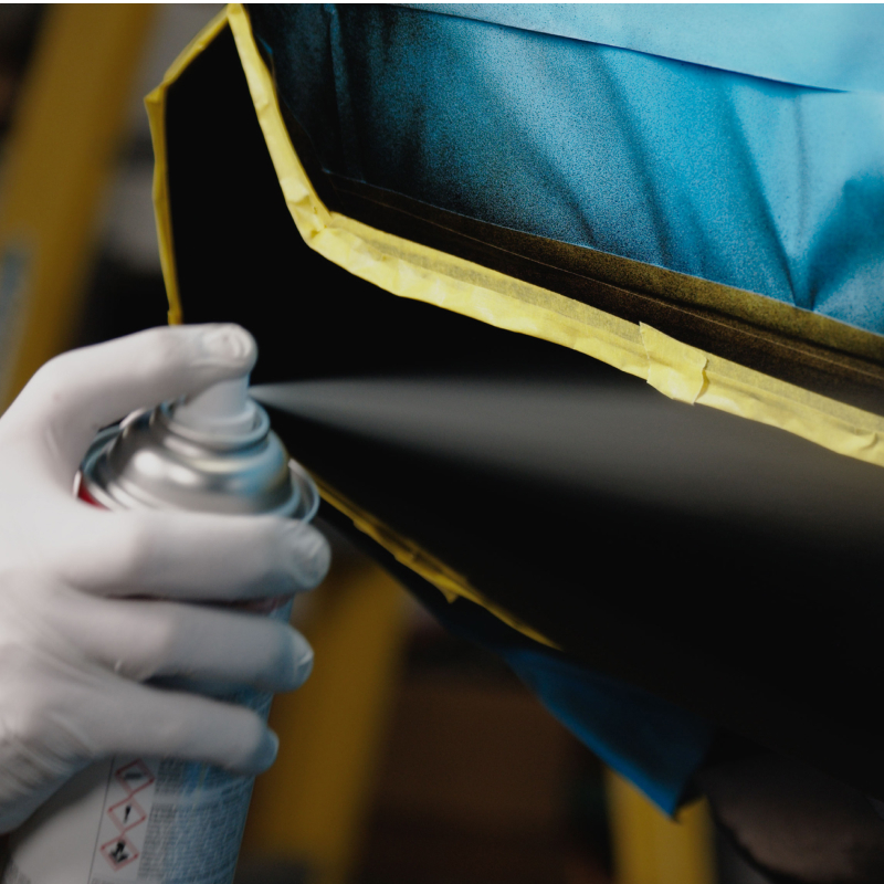 Gloved hand applying additional colorcoat layers to achieve complete paint coverage.