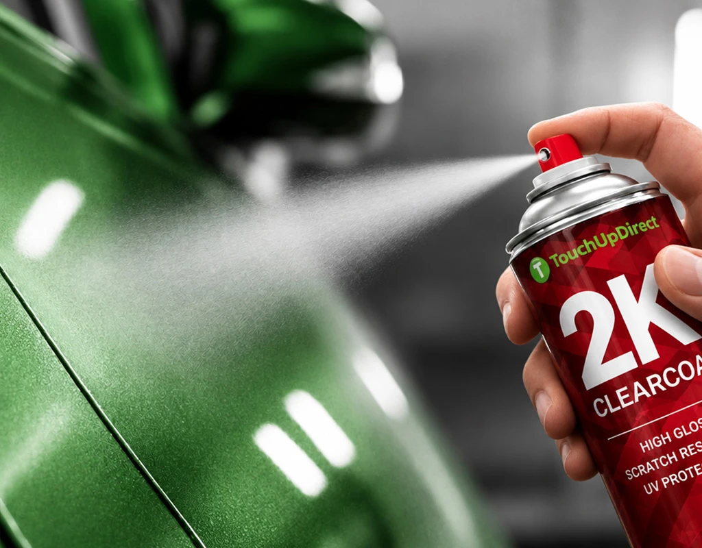 lack-gloved hand holding a TouchUpDirect 2K clearcoat aerosol can in front of a red vehicle panel.