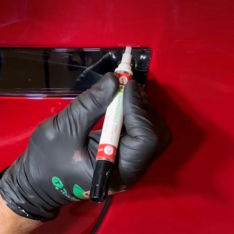 Gloved hand applying clearcoat with a combo applicator on a red vehicle panel